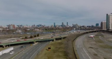 İleri, çok şeritli yol kavşağının üzerinden uçar. Modern yüksek gökdelenlerle şehir manzarasını gözler önüne seriyor. Boston, ABD