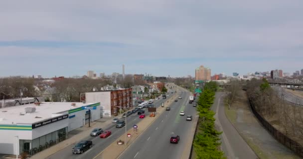 Flygfoto av fordon som kör på flerfilig väg i stadsdelen. Kommersiella byggnader och bostadshus längs gatan. Boston, USA — Stockvideo