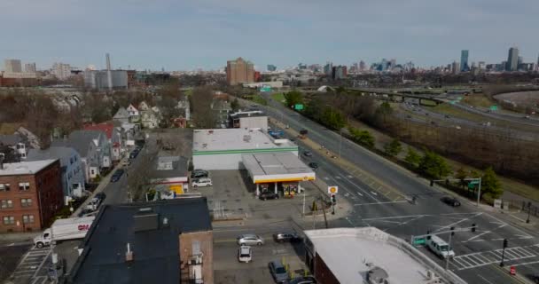 Orbit shot around of gas station on corner. Vehicles passing through road intersection in urban neighbourhood. Boston, USA — 비디오