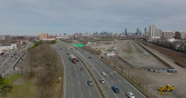 Fly above busy multilane trunk road. Highway leading in suburbs, high rise downtown buildings in distance. Boston, USA — Video