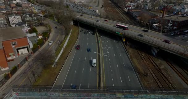 Backwards fly above busy multilane trunk road. Tilt up reveal of cityscape with downtown skyscrapers in distance. Boston, USA — 비디오