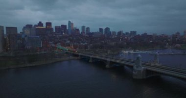 Bulutlu bir günde alacakaranlıkta Charles nehri ve şehir manzarası üzerinde büyük bir köprü. Su yüzeyinden geriye doğru inen sinek. Boston, ABD
