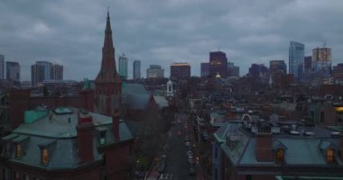 Evleri ve kırmızı tuğlalı cepheleri olan kiliseleri olan şehir merkezinin üzerinden uç. Alacakaranlıkta yerleşim yeri. Boston, ABD