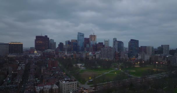 Hátrafelé repül a városrész felett. Modern, toronymagas irodaházak csoportja alkonyatkor a felhős ég ellen. Boston, Egyesült Államok — Stock videók