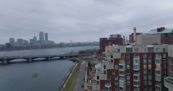 Voorwaarts vliegen rond moderne appartementengebouwen aan de waterkant. Brug over brede rivier en kantoortorens aan andere oever. Boston, Verenigde Staten — Stockvideo