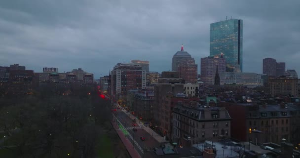 Kvällsflyg över park och byggnader i stadsdelen. Trafiken på gatorna. Modern höghus byggnad mot himlen i skymningen. Boston, USA — Stockvideo