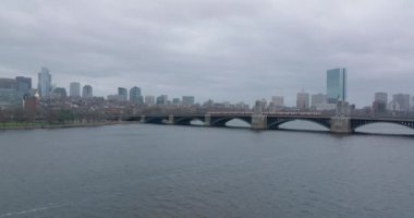 Longfellow Köprüsü 'nde arka planda şehir ilçesi olan kırmızı hat treni sürüyor. İleri, dalgalı su yüzeyinin üzerinde uçar. Boston, ABD