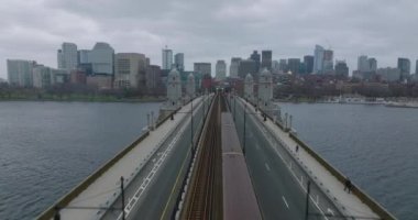 İleri, Longfellow Köprüsü üzerinde tren ve arabalarla uçar. Bulutlu gökyüzüne karşı şehir merkezindeki binalar. Boston, ABD