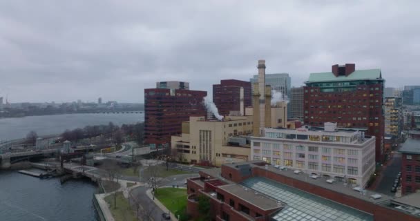 Skjut och panorera skott av fabrik eller värmestation med skorstenar på flodbanken. Byggnader i stadsområden. Boston, USA — Stockvideo