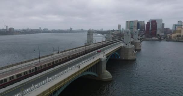 Verfolgung eines Zuges der roten U-Bahn-Linie, der an einem bewölkten Tag auf der Longfellow Bridge über den breiten Charles River fährt. Boston, USA — Stockvideo