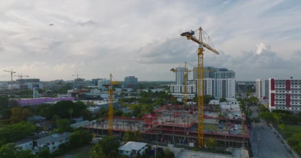 Adelante vuelan por encima del sitio de construcción con maquinaria. Grupo de grúas amarillas ayudando con la construcción de una nueva estructura en la ciudad. Miami, Estados Unidos — Vídeos de Stock