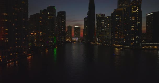 Cinematic evening shot of tall buildings along river. Silhouettes on high rise apartment houses against colourful twilight sky. Miami, USA — Stock Video