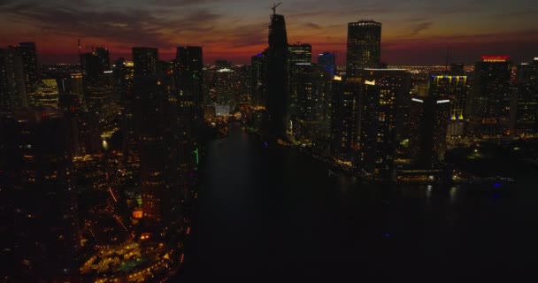 Aerial descending footage of city at night. Silhouettes of downtown high rise apartment buildings against colourful twilight sky. Miami, USA — Stock Video