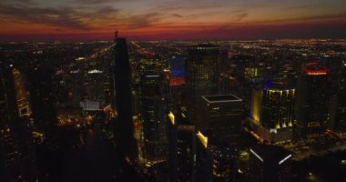 Arka planda, kırmızı alacakaranlık gökyüzü altında modern yüksek katlı apartman binalarının ve yerleşim yerlerinin hava indirme görüntüleri var. Miami, ABD