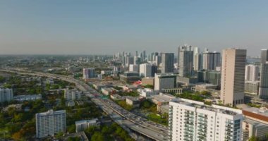 Şehir merkezinin hava panoramik manzarası. Yoğun çoklu şeritli otoyolda aşağı eğil ve uzun gölgeler bırakan parlak alçak güneş. Miami, ABD
