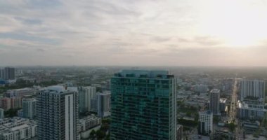 Şehirdeki modern yüksek binaların üzerinden uç. Gün batımında yerleşim yerinin panoramik manzarası gözler önüne seriliyor. Miami, ABD