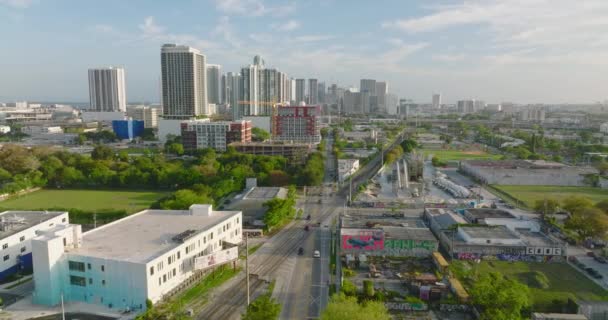 Flygfoto panoramautsikt över storstaden. Fordon som kör på väg och korsar järnvägsspår. höghus i bakgrunden. Miami, USA — Stockvideo