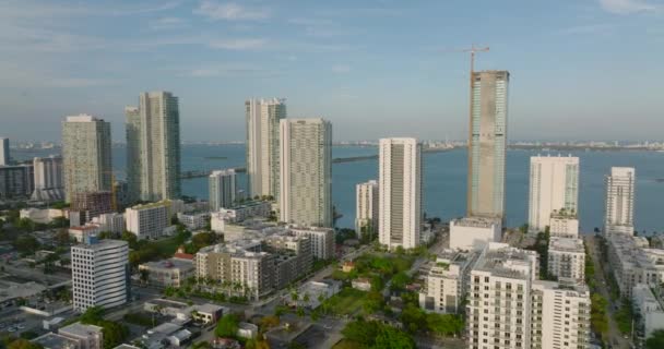 Dopředu létají nad městskou čtvrtí. Řada moderních vysokých obytných budov na nábřeží osvětlená jasným sluncem. Miami, USA — Stock video