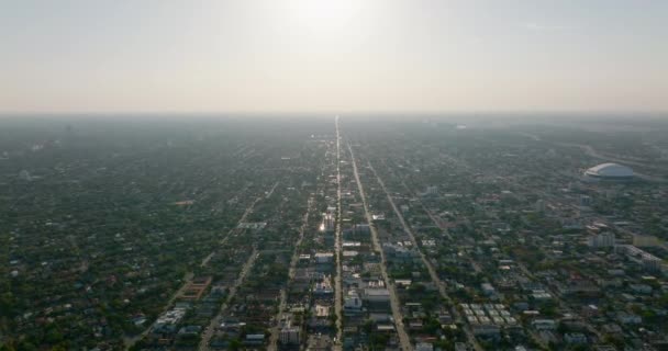 Flygfoto av stort område täckt med låga bostadshus omgivna av träd och grönska. Visa mot nedgående sol. Miami, USA — Stockvideo