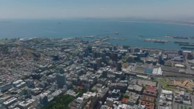 Deniz kıyısındaki yüksek açılı şehir manzarası. Şehir merkezinde, tren istasyonunda ve limanda yüksek binalar. Cape Town, Güney Afrika.