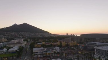 Alışveriş ve eğlence semtindeki binaların tersten ifşası. Gün batımına karşı şehir ve tepeler. Cape Town, Güney Afrika.