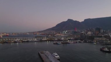 Alacakaranlıkta yat limanının kaydırağını çek. Şehir ve Masa Dağı arka planda alacakaranlık gökyüzüne karşı. Cape Town, Güney Afrika.