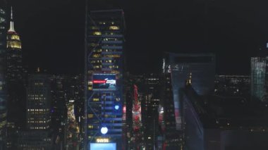 Geceleri şehir merkezindeki gökdelenlerin iniş görüntüleri. Görsel efektler ön cepheye büyük ekran ekliyor. Manhattan, New York City, ABD.