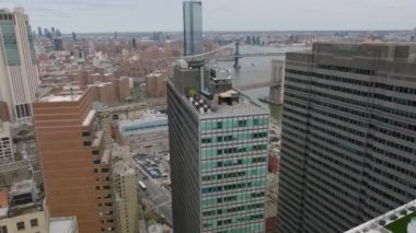 İleri, modern yüksek binaların üzerinden uçar. Nehir kıyısındaki işlek yolları ve köprüleri gösteriyor. Manhattan, New York City, ABD.