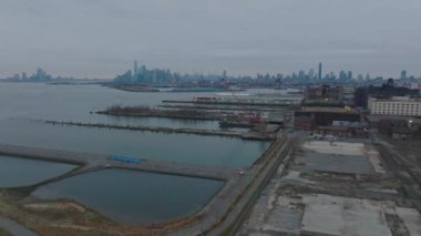 Güney Brooklyn 'deki terk edilmiş rıhtımların üzerinde Manhattan ve iş gökdelenleri manzaralı forvetler uçuyor. New York City, ABD.