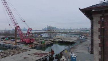 Endüstriyel bölgenin üzerinden uçmak. Eski rıhtımlardaki terk edilmiş rıhtımlar. Yükseklerdeki binalarla ufuk çizgisi açığa çıkıyor. New York City, ABD.