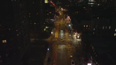 Şehir merkezinde çok katlı binalarla çevrili caddenin üzerinde uç. Gece şehri sahnesi. Manhattan, New York City, ABD.