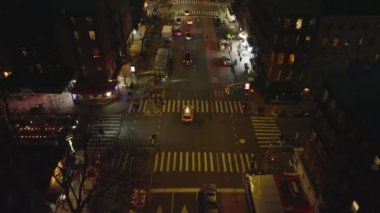 Gece şehrinin sokaklarında dolaşan tipik sarı taksiyi takip ediyor. Yol kavşağından geçen taksinin yüksek açılı görüntüsü. Manhattan, New York City, ABD.
