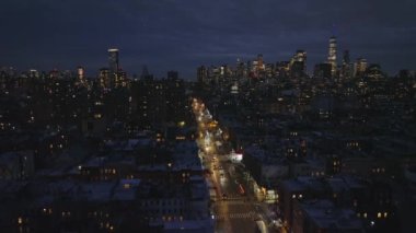 Forwardlar düz ve parlayan caddelerin üzerinden uçarak şehir merkezindeki apartman dairelerinin arasından geçerler. Şehir merkezinde arka planda gökdelenler olan gece manzarası. Manhattan, New York City, ABD.