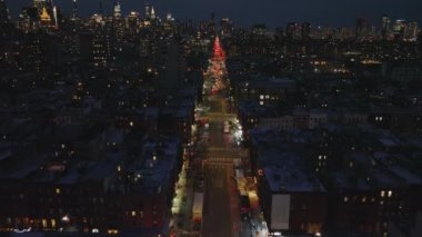 Şehirdeki uzun düz caddenin üzerinden geriye doğru uç. Şehir merkezindeki ünlü yüksek binalarla gökdelenleri gözler önüne seriyor. Gece şehri sahnesi. Manhattan, New York City, ABD.