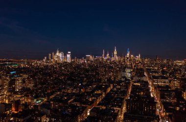 Gece manzarası. Şehir gelişimindeki ışıklı pencereler ve uzaktan aydınlatılmış gökdelenler. Manhattan, New York City, ABD.