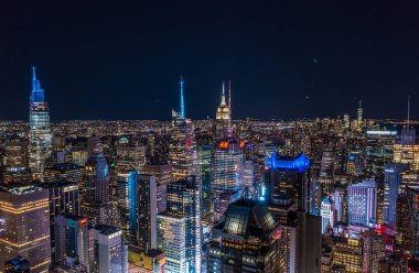 Gece büyük şehirde binlerce ışık yanar. Yüksek gökdelenli renkli binaların panoramik görüntüsü. Manhattan, New York City, ABD.
