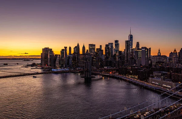 Manhattan 'ın aşağısındaki gökdelenler renkli günbatımı gökyüzüne karşı. Su boyunca yoğun trafik var. Manhattan, New York City, ABD.