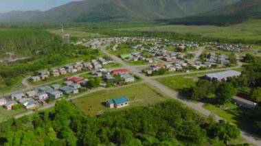 High angle view of low buildings in village in countryside. Tilt up reveal of mountain ridge. South Africa.
