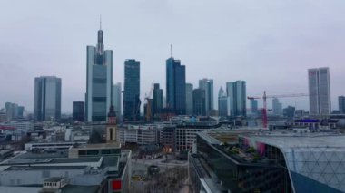 İleri, Rossmarkt etrafındaki binaların üzerinden uçuyor. Alacakaranlıkta bulutlu gökyüzüne karşı modern şehir merkezi gökdelenleri. Frankfurt am Main, Almanya.