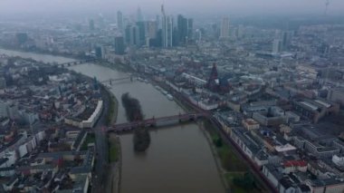 Şehir merkezindeki nehir boyunca yüksek açılı bir bina. Eğim şehir merkezindeki gökdelenlerin puslu manzarasını ortaya çıkarıyor. Frankfurt am Main, Almanya.