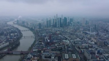Metropolis 'in üzerinden uç. Şehir merkezindeki bir grup gökdelen şehir merkezinden yükseliyor. Nehir boyunca uzanan köprü. Frankfurt am Main, Almanya.
