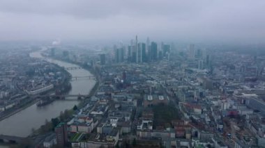 Sisli bir günde büyük şehrin hava panoramik görüntüleri. Şehrin içinden akan geniş bir nehir. Bir grup modern şehir merkezi gökdelenleri. Frankfurt am Main, Almanya.
