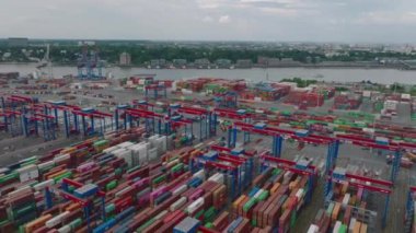 Aerial view of traffic in logistic terminal. Forwards fly above rows of containers and moving cranes and vehicles. Intermodal transport and global logistics. Hamburg, Germany.