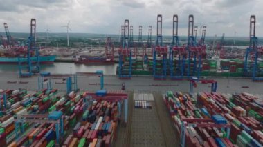 Slider of machinery in harbour cargo terminal. Aerial view of stacked overseas containers and majestic gantry cranes loading large ships. Intermodal transport and global logistics. Hamburg, Germany.