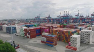 Aerial ascending footage of varied colour standardised containers stacked in large harbour. Important transport crossroads for importing and exporting abroad. Hamburg, Germany.