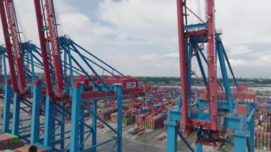 Fly around large gantry cranes in harbour. Revealing logistic terminal with rows of naval containers. Intermodal transport and global logistics. Hamburg, Germany.