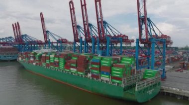 Majestic cargo ship with loaded thousands of overseas containers. Ascending footage of cargo terminal in harbour. Intermodal transport and global logistics. Hamburg, Germany.