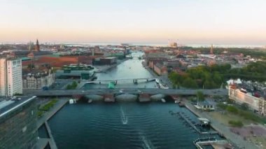Hyperlapse shot of boats passing through city on water surface. Forwards fly above large city at twilight. Copenhagen, Denmark.