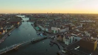 Forwards fly above historic city centre. Aerial hyperlapse footage of metropolis at sunset. Landmarks with towers and traffic on town water canal. Copenhagen, Denmark.