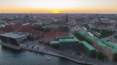 Aerial hyperlapse shot of complex of historic buildings of Royal Library and Christiansborg Palace on Slotsholmen islet. Forwards fly above historic city centre at dusk. Copenhagen, Denmark.
